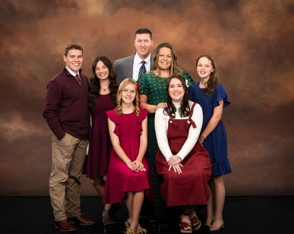 A family gathers around a young man in the center, all smiling for a group photo together.