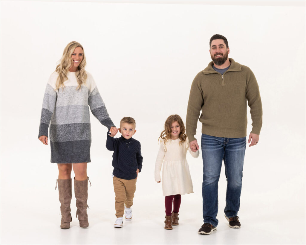 A family poses together in front of a plain white background, showcasing their unity and togetherness.